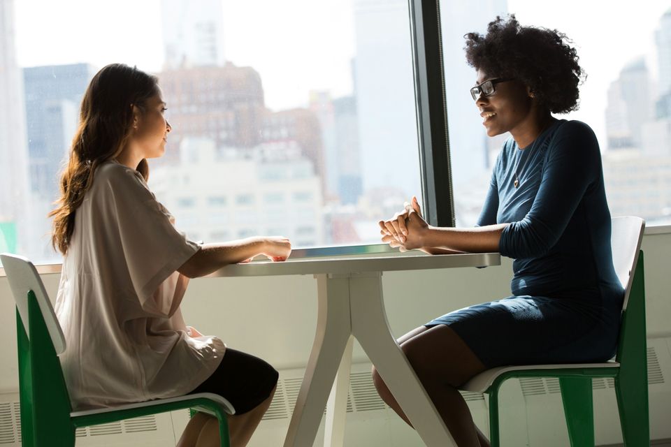 Two Women sitting on table (unsplash)